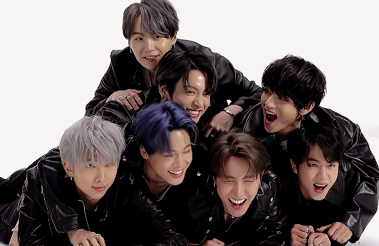 Gif of BTS, huddled on top of one another and laughing